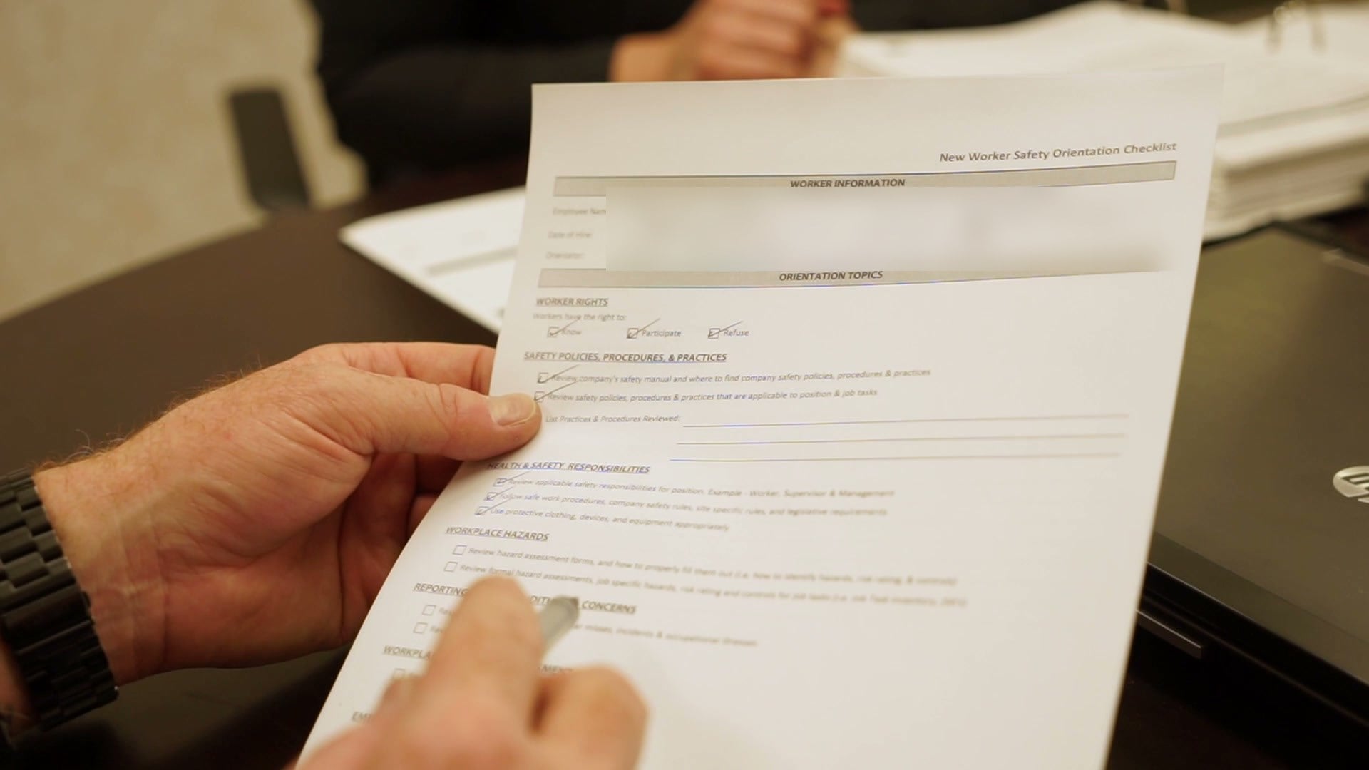 A completed new worker safety orientation checklist being reviewed at a desk.